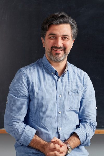 Adult teacher posing on blackboard.